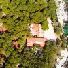 Vista aerea di una casa tra gli alberi vicino al mare.