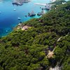 Area forestale con scogliere e mare azzurro.