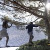 Persone camminano su una rete tra gli alberi.