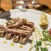 Piatti di pesce grigliato con limone, pomodori e foglie verdi su un piatto bianco.