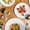 Tavola con vari piatti di cibo, tra cui pasta e frutti di mare, vista dall'alto.