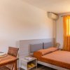 Una stanza luminosa con un letto arancione, tende arancioni, tavolo, e sedie in legno.