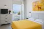 Stanza luminosa con letto giallo e balcone.