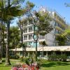 Un edificio alberghiero circondato da alberi e prati fioriti.