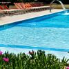 Piscina con sdraio arancioni e un piccolo giardino fiorito.