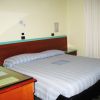 Letto matrimoniale accanto a una finestra con tende bianche.