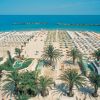 Vista dall'alto di una spiaggia con palme e ombrelloni.