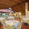 Ampia sala ristorante con tavoli apparecchiati, sedie bianche e tetto di legno.