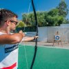 Uomo che pratica tiro con l'arco su un campo all'aperto.