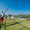 Gruppo di persone gioca a pallavolo su un campo erboso.