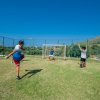 Tre persone giocano a calcio vicino a una porta su un campo verde.