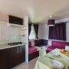 Interno di una casa mobile con cucina, tavolo apparecchiato e divano con tende viola.
