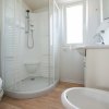 Un bagno moderno con cabina doccia arrotondata, wc, lavabo e bidet, pavimento in legno chiaro.