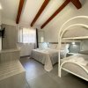 Interno di una stanza con letto matrimoniale, letti a castello, travi in legno e TV a parete.