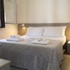 Camera da letto con letto matrimoniale, coperte grigie e due comodini con luci accese.