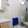 Bagno moderno con lavabo, bidet, WC, asciugacapelli e doccia con porta in vetro.