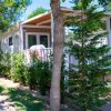 Esterno di un bungalow con veranda, immerso nel verde con bicicletta parcheggiata di lato.