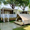 Bungalow in legno con veranda bianca e piccola tenda accanto su prato.