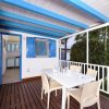 Terrazza coperta con tavolo bianco, quattro sedie e vista sul giardino.