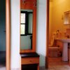 Corridoio con specchio e appendiabiti, porta verso bagno con wc e lavandino visibili.