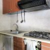 Cucina con piano cottura, lavello e utensili pendenti, rifinita con mattoni e piastrelle.