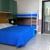 Camera con letto matrimoniale e letti a castello. Bagno visibile sullo sfondo.