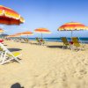 Spiaggia con ombrelloni arancioni e gialli e sedie a sdraio in fila.