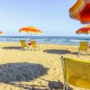 Ombrelloni colorati sulla spiaggia, con sdraio di fronte al mare.