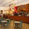 Interno di un bar con sedie e tavoli, un bancone lungo e decorazioni rustiche.