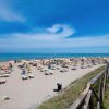 Spiaggia sabbiosa con lettini e ombrelloni colorati.