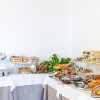 Tavolo buffet con torte, frutta e dolci vari su tovaglie bianche.