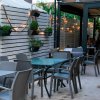 Patio con tavoli, sedie e luci decorative sulle pareti.
