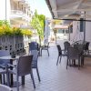 Spazio esterno con tavolini, sedie e ombrelloni, circondato da piante.