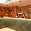 Bar con bancone moderno, luci pendenti nere e scaffali di bottiglie.