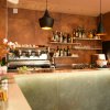 Dettaglio del bancone del bar con macchina da caffè e luci pendenti.