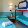 Una camera con letto singolo e letto a castello, copriletti azzurri e asciugamani bianchi.