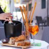 Snack con pane, grissini e cocktail su un tavolo all'aperto.