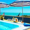 Piscina con ombrelloni a strisce blu e bianche.