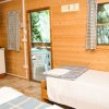 Interno di una cabina in legno con due letti, angolo cottura e vista su una porta finestra.