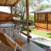 Veranda con tavolo e sedie di plastica affacciata su un giardino con bungalow in legno.