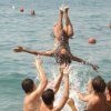 Persone in mare che lanciano una ragazza in aria durante un gioco in acqua.