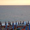 Tramonto su spiaggia con ombrelloni colorati e mare.