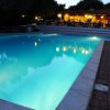 Piscina illuminata di sera con ristorante sullo sfondo.