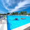 Uomo in piedi su una piattaforma accanto a una piscina, cielo limpido.