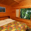 Camera con letto matrimoniale, coperta colorata e finestra vista alberi.