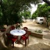 Tavolo rotondo con sedie rosse in un giardino con alberi e roulotte.