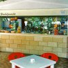 Un bar con sedie rosse e tavolo bianco all'aperto, circondato da piante.