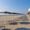 Spiaggia con file di lettini e ombrelloni chiusi che si estendono verso il mare.