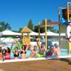 Persone sorridenti in una piscina accanto a una statua di tartaruga con salvagente.