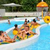 Persone su gommoni in un fiume lento in piscina, sotto il sole.